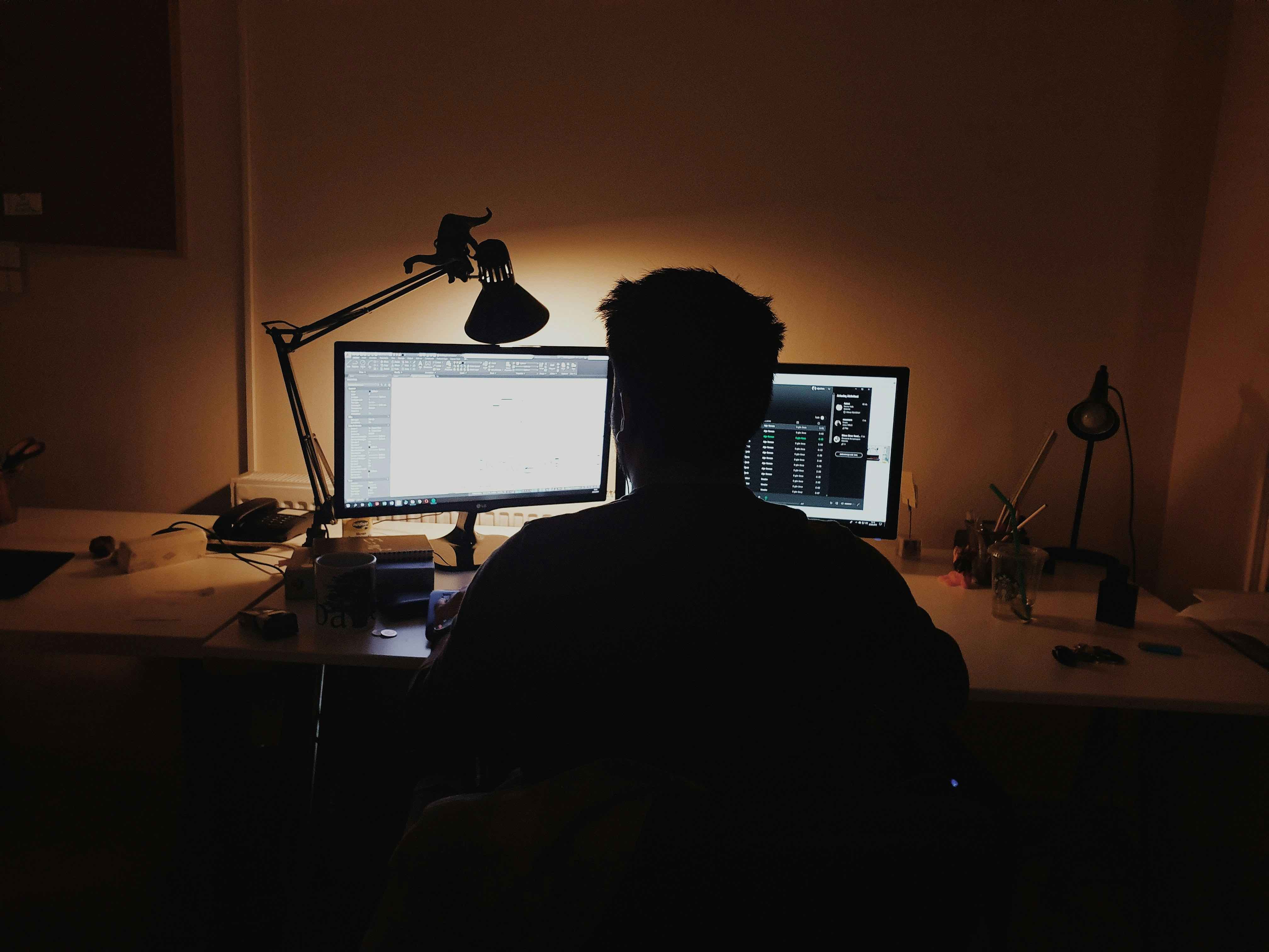 A developer on a video call with a grid of participant tiles on screen and a short note open in a second window.